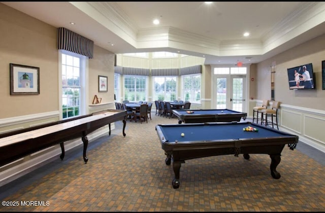 recreation room with a wealth of natural light, a decorative wall, and a raised ceiling