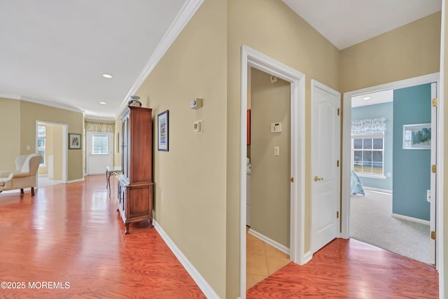 hallway with ornamental molding and light hardwood / wood-style floors