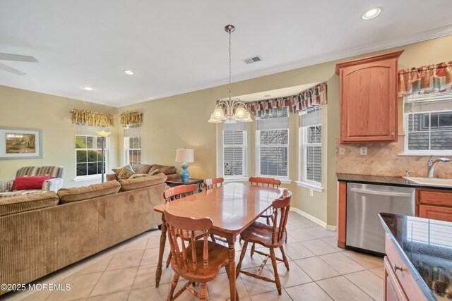 dining room with crown molding, ceiling fan with notable chandelier, sink, and light tile patterned floors