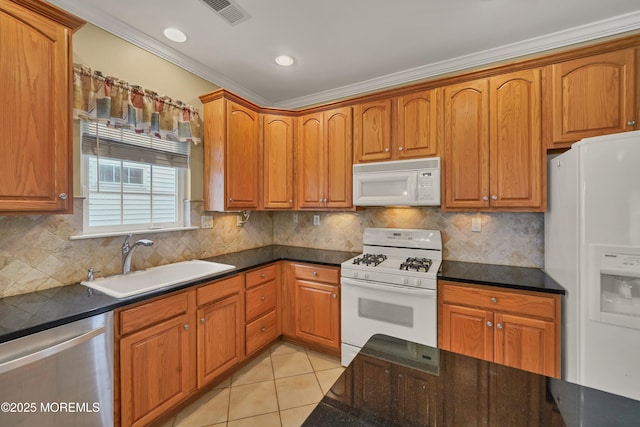 kitchen with sink, white appliances, light tile patterned flooring, decorative backsplash, and dark stone counters