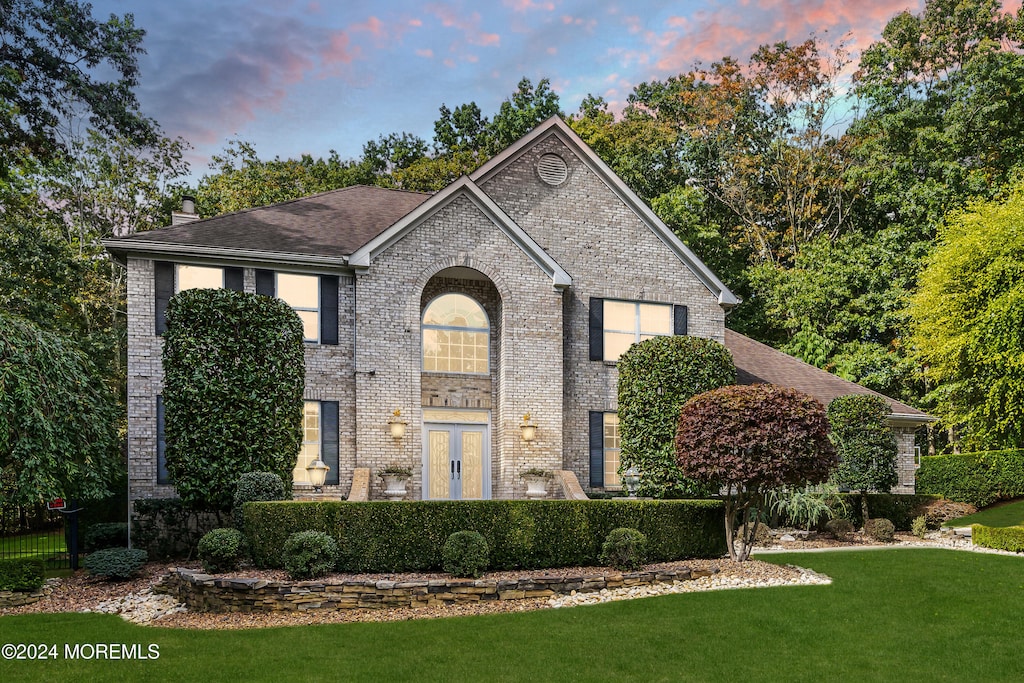 view of front of house with a lawn and french doors