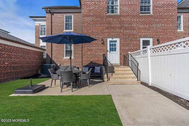 rear view of property featuring central AC unit, brick siding, fence, a yard, and a patio area