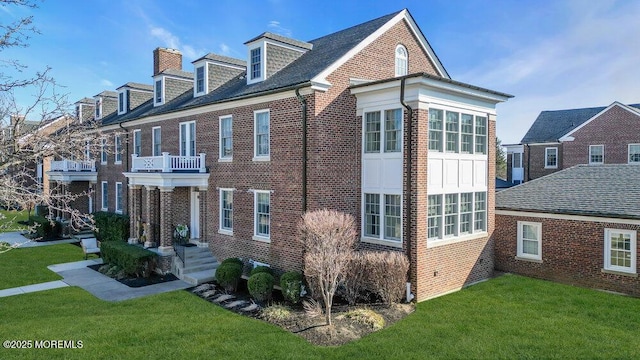 view of side of property featuring a yard, brick siding, and a chimney