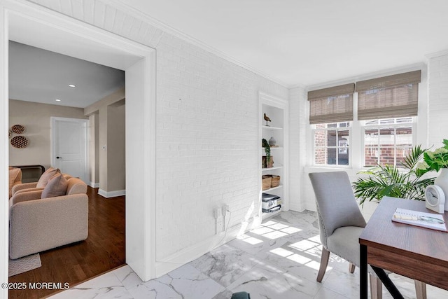 home office featuring built in features, marble finish floor, crown molding, brick wall, and baseboards