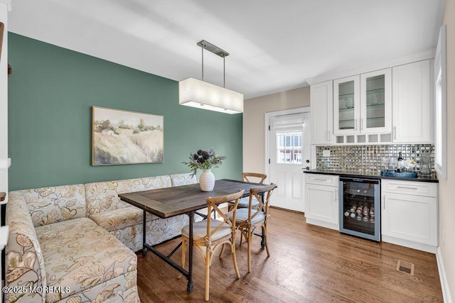 dining room with beverage cooler, a dry bar, wood finished floors, and visible vents