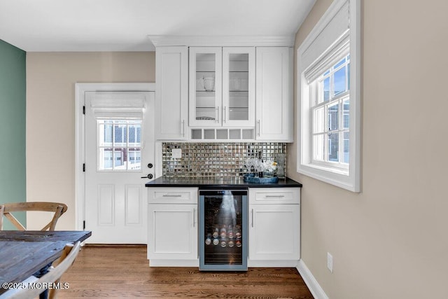 bar with dark wood-style flooring, a dry bar, decorative backsplash, beverage cooler, and baseboards