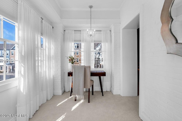 carpeted dining room featuring a notable chandelier, brick wall, ornamental molding, and a healthy amount of sunlight