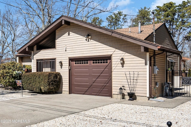 exterior space with concrete driveway, an attached garage, and a shingled roof