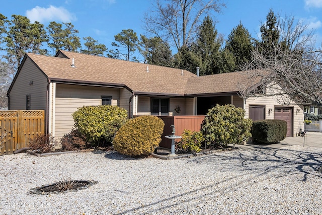 ranch-style house featuring driveway, a shingled roof, a garage, and fence