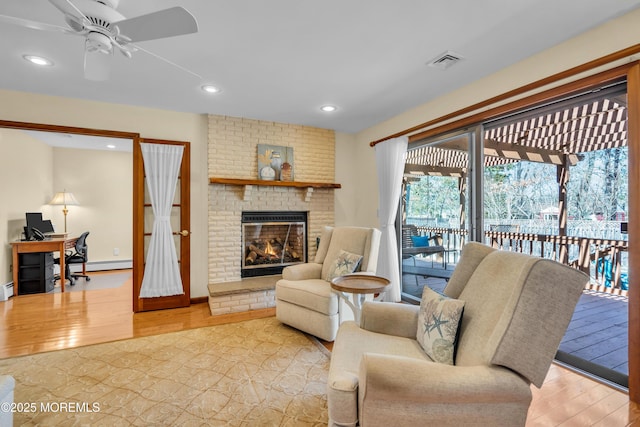 living area with a ceiling fan, visible vents, recessed lighting, a brick fireplace, and light wood-type flooring