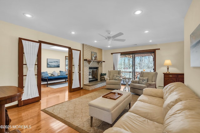 living area featuring a brick fireplace, recessed lighting, light wood-type flooring, and baseboard heating