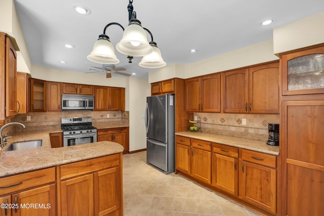 kitchen featuring light stone counters, brown cabinets, appliances with stainless steel finishes, and a sink