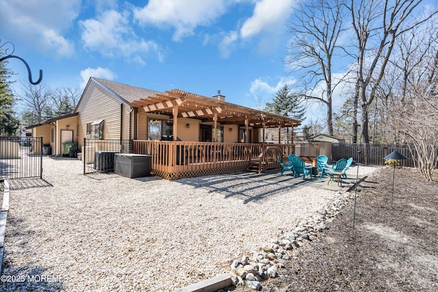 rear view of house with fence, a wooden deck, a chimney, a pergola, and a patio