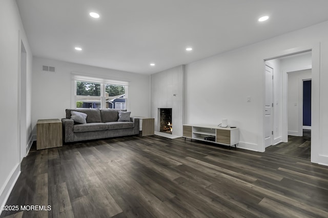 living room with a large fireplace and dark hardwood / wood-style flooring