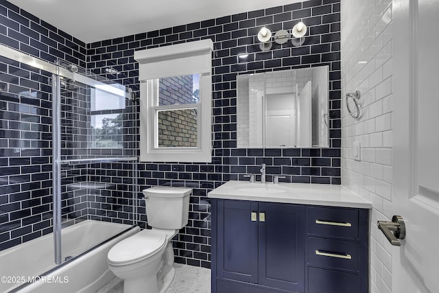 full bathroom featuring bath / shower combo with glass door, tile walls, decorative backsplash, vanity, and toilet