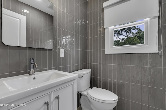 bathroom with vanity, tile walls, and toilet