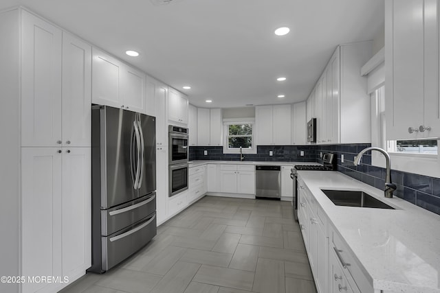 kitchen with light stone countertops, white cabinetry, appliances with stainless steel finishes, and sink