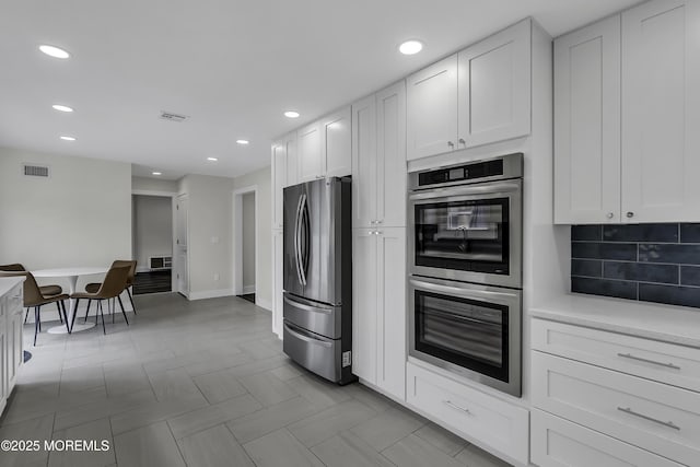 kitchen featuring white cabinetry, appliances with stainless steel finishes, light parquet flooring, and backsplash