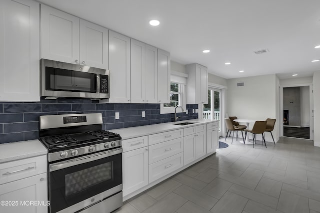 kitchen with stainless steel appliances, sink, and white cabinets