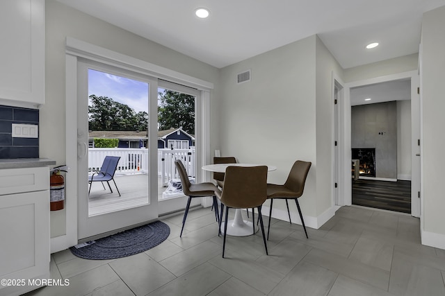 tiled dining room featuring a large fireplace