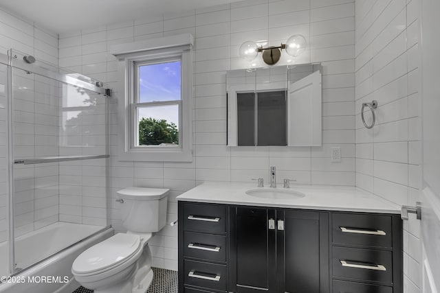 full bathroom with tile walls, bath / shower combo with glass door, vanity, decorative backsplash, and toilet