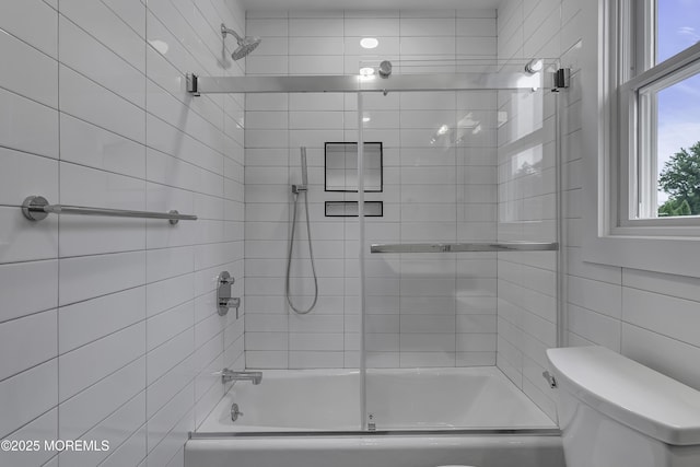 bathroom featuring toilet and combined bath / shower with glass door