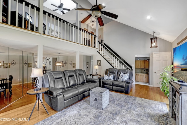 living room with ceiling fan with notable chandelier, high vaulted ceiling, and hardwood / wood-style floors