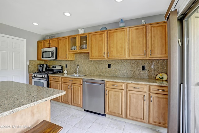 kitchen featuring sink, light stone counters, light tile patterned floors, stainless steel appliances, and decorative backsplash