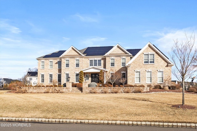 view of front of home with a front yard and solar panels