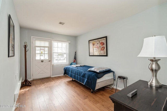 bedroom with visible vents, baseboards, and wood finished floors