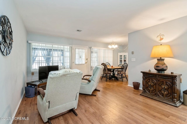 living area with a chandelier, light wood finished floors, and baseboards