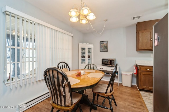 dining room with baseboards, visible vents, a baseboard radiator, light wood-style flooring, and a notable chandelier