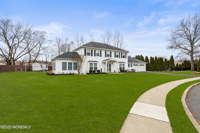 view of front of house with a front yard, fence, a chimney, and an attached garage