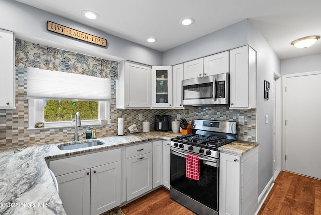 kitchen featuring stainless steel appliances, a sink, dark wood finished floors, and white cabinetry