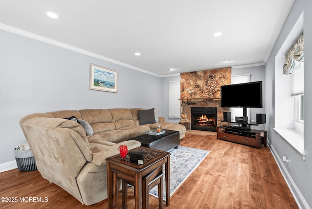 living area featuring recessed lighting, ornamental molding, a stone fireplace, light wood-type flooring, and baseboards