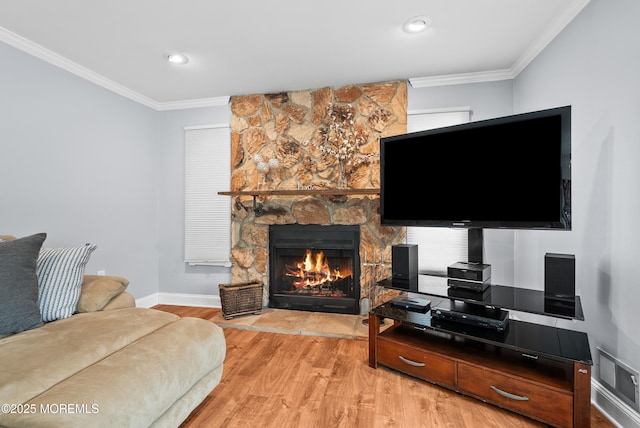 living area with a fireplace, visible vents, light wood-style flooring, ornamental molding, and baseboards