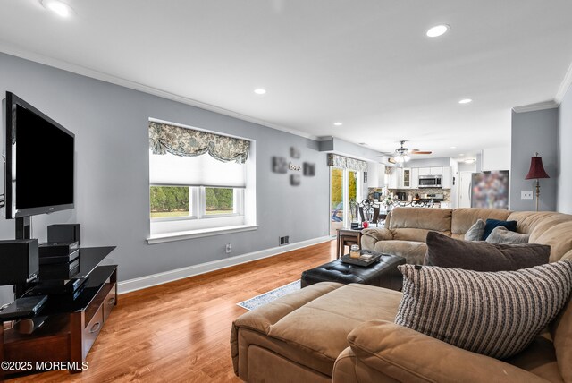 living room featuring baseboards, visible vents, ornamental molding, light wood-type flooring, and recessed lighting