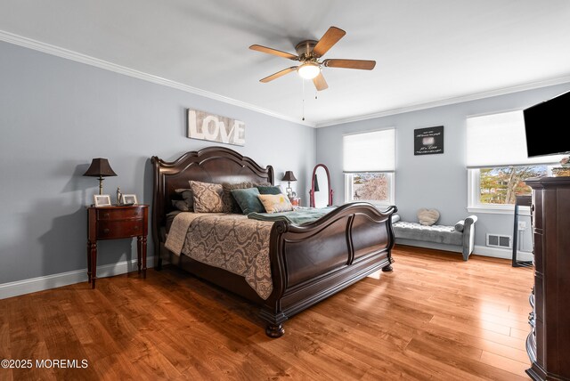 bedroom featuring light wood-type flooring, visible vents, baseboards, and crown molding