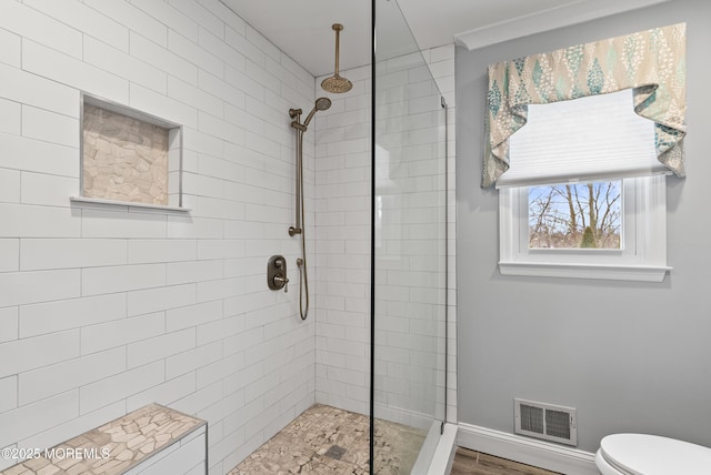 bathroom featuring toilet, visible vents, and a tile shower