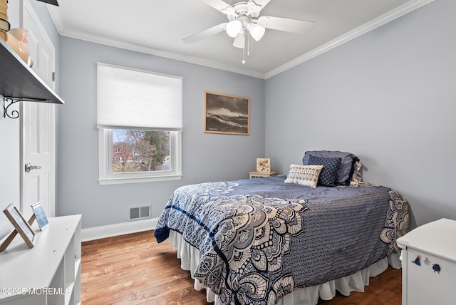 bedroom with light wood finished floors, baseboards, visible vents, and crown molding