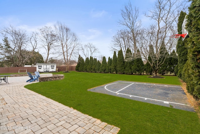 view of yard with a patio area, a fenced backyard, community basketball court, and an outdoor structure