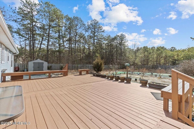 wooden deck with an outbuilding, a fenced backyard, and a shed