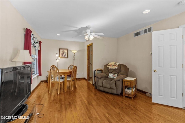 living area with baseboards, a ceiling fan, visible vents, and light wood-style floors