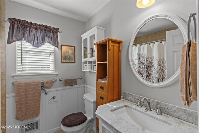 full bath featuring wainscoting, vanity, and toilet