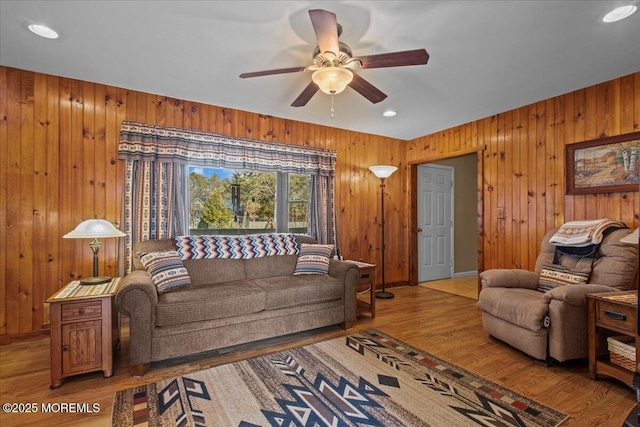 living area featuring wood walls, a ceiling fan, and wood finished floors