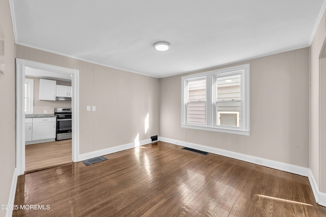 spare room featuring ornamental molding and dark hardwood / wood-style flooring