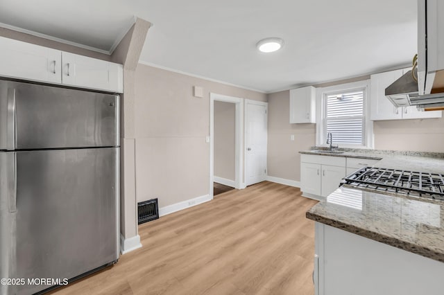 kitchen featuring stainless steel refrigerator, light stone countertops, sink, and white cabinets