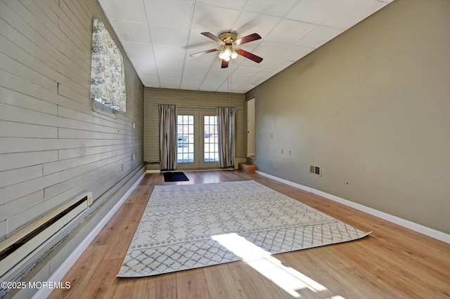 doorway with ceiling fan, wood-type flooring, and wood walls