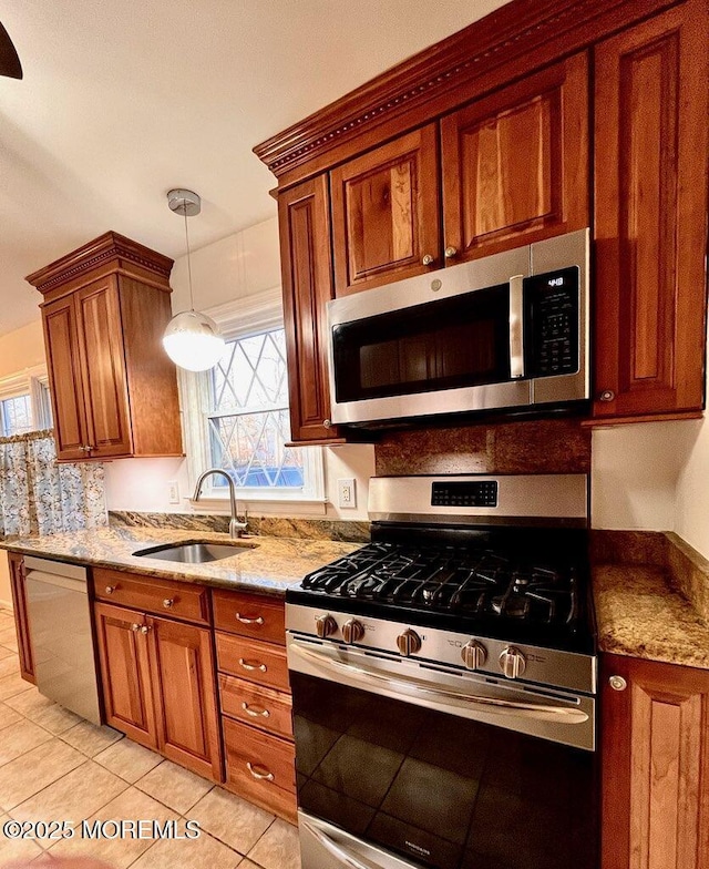 kitchen featuring appliances with stainless steel finishes, sink, light tile patterned flooring, decorative light fixtures, and light stone countertops