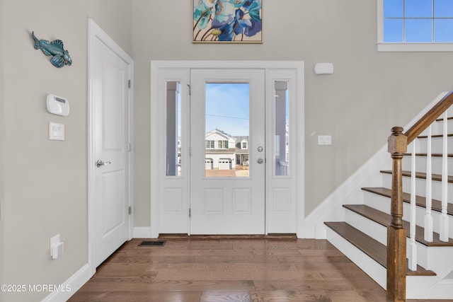 entrance foyer with dark wood-style floors, a wealth of natural light, visible vents, and stairs